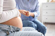 © Pixel-Shot - Young pregnant woman with doula holding hands in bedroom, closeup
