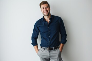 smiling man wearing a navy blue shirt and gray pants on a white background