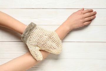 Female hands with massage glove on light wooden background, closeup