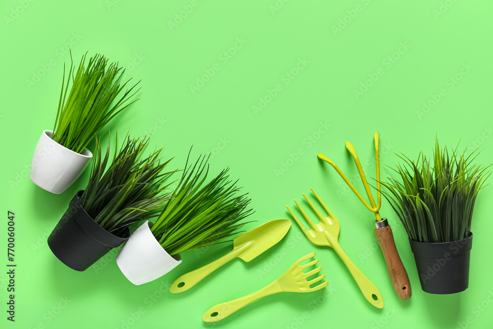 Gardening tools and plants in pots on green background