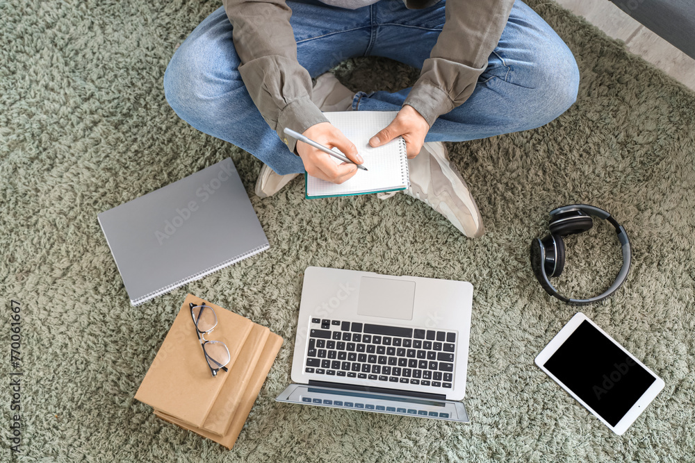 Male student with laptop studying online on carpet, top view