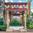 Charming stone gazebo with carved columns nestled amidst lush greenery in a serene urban garden