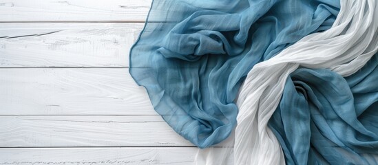 Wall Mural - An aerial perspective of a white wooden table with a linen kitchen towel or fabric napkin. A blue tablecloth drapes over the white wood surface. Empty space available for text.