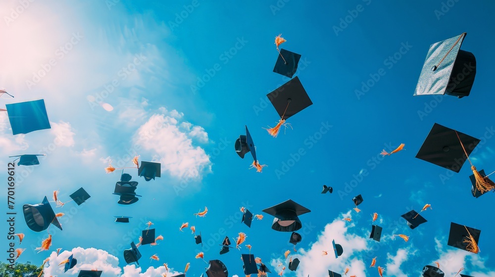 Graduation day, caps flying in the air with a clear blue sky background ...