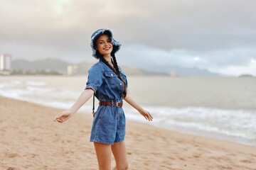 Wall Mural - Beautiful young woman enjoying a summer vacation on a tropical beach, surrounded by the stunning nature of the ocean and sky. She is an attractive lady, with long, flowing hair, wearing a stylish