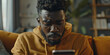a close up shot of an African American man with short hair and beard wearing a sweatshirt looking at his phone in the living room, generative AI