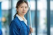 © Larisa - A professional cleaner in blue uniform holding a mop, ready to tidy up the space.