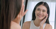 Young woman feels confident and proud of her face while standing in front of the mirror.