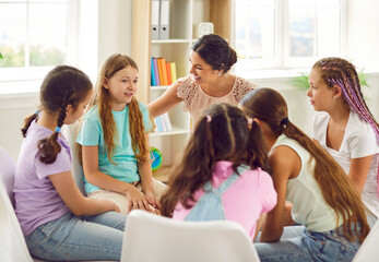 Wall Mural - Children having a discussion in group therapy. Group of kids who are school friends talking with their school psychologist. Several happy girls sitting in a circle and talking