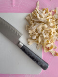 Fototapeta Tulipany - raw fettuccine pasta and knife on cutting board