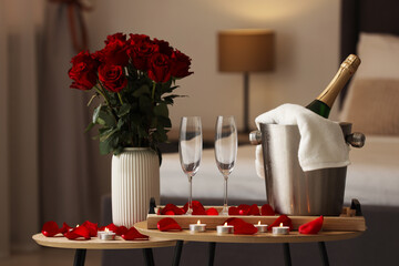 Sticker - Honeymoon. Sparkling wine, glasses and bouquet of roses on wooden table in room