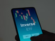 An investor analyzing the inverse etf fund on a screen. A phone shows the prices of Inverse
