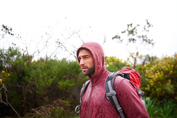 Wall Mural - Extreme, hiking and man in rain, walking and holiday for survival adventure, outdoor and trekking. Water, traveller and male person with backpack in tough environment, rough and destination of Europe