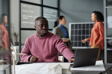 Leinwandbilder - Young serious male entrepreneur or architect pressing key of laptop keyboard and looking at screen while sitting by workplace