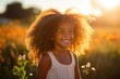 Smiling dark skinned little girl standing in a blurred background field with golden hour light