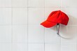bright red cap on a sleek silver hook against a white tiled wall