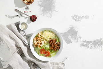 Canvas Print - Fresh Caesar salad with grilled chicken, croutons, and shaved cheese in a white bowl, top view on a textured backdrop