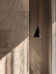 Wall Mural - Close-up of a wall with vertical lines and soft lighting. The wall is decorated with marble. A triangular black lamp hangs from above, casting gentle shadows on the surface of the wall.