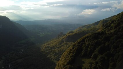 Wall Mural - Landscape aerial of green slope mountains with plains and gray cloudy sky on the horizon