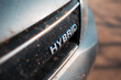 Close-up of Hybrid icon on dirty car body. Environment concept. Ecological transport.