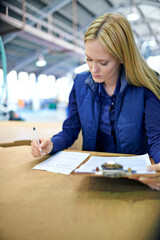 Wall Mural - Business woman, writing and checking inventory with clipboard, storage or supply chain at warehouse. Female person, job manager or employee with for documents, paperwork or distribution at factory
