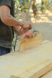 Close up of sanding a wood with orbital sander at workshop