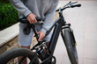 © Taras Grebinets - Cropped view man cyclist adjusting a seat on an electric motor bike while renting e-bike as eco-friendly urban transport