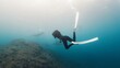 Underwater photographer takes picture of manta ray. Freediver with camera films Giant ocean Manta Ray swimming over reef. Nusa Penida, Bali, Indonesia
