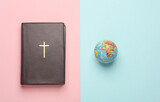 Fototapeta Mapy - Bible book with globe on a pink blue background. Christian religion