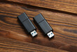 Two black USB flash drives on wooden table