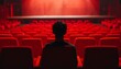 Solitary figure sits in theater's red seat, gazing ahead, cinematic ambiance