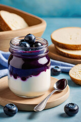 Wall Mural - Delicious yogurt or parfait with blueberry sauce and blueberry in glass jar on a pastel background, summer breakfast.