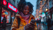 Cheerful young woman in a yellow jacket browsing her phone on a snowy city street with blurred lights
