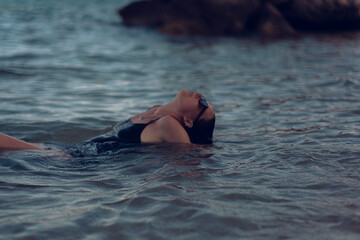 A young beautiful girl posing in the water on the sea beach