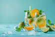 Two glasses with mojito cocktails with ice cubes, orange, lime slices and mint leaves on blue background. Refreshing summer drinks. Copy space.