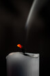 Glühender Kerzendocht mit Rauch von vergangenem Feuer vor dunklem Hintergrund