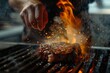 A chef is seasoning a sizzling steak on a grill with flames rising while cooking