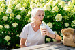 Portrait of attractive cheerful grey-haired woman spending free time drinking latte rest relax strolling outdoors