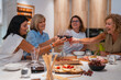 © Alberto Rojas/Stocksy - Company of women toasting with wineglasses above table