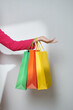 © Marc Tran/Stocksy - Crop female hand holding colorful paper bags on background
