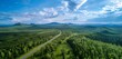 Drone shot of the valley road in Sainte-Marguerite between trees and mountains in the background, A straight high-way road through green ecological lush trees forest environment. Generative AI