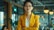 The dynamic presence of an Asian female leader, attired in a vibrant yellow suit, symbolizing innovation and ambition within the confines of her office space.