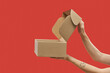 © Yaroslav Danylchenko/Stocksy - Side view of female hands opening cardboard box over red background