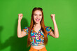 Photo portrait of attractive young woman raise fists winning dressed stylish retro clothes isolated on green color background