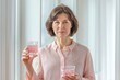 A middle-aged woman in a pink blouse drinks liquid collagen for facial skin care. Vitamins. Supplements.