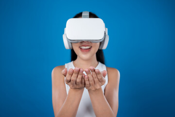 Smart female standing with blue background wearing VR headset connecting metaverse, futuristic cyberspace community technology. Elegant woman excited seeing generated virtual scenery. Hallucination.