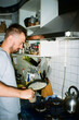 © Volya Tarasava/Stocksy - UGC portrait of young man cooking pancakes at home