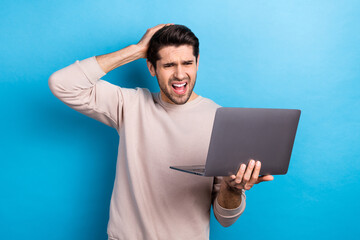 Sticker - Photo of dissatisfied man with stylish haircut dressed beige sweatshirt hold laptop arms on head isolated on blue color background