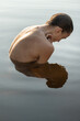 © Andriy Bezuglov/Stocksy - Wet topless model reflected on water surface while posing outdoo
