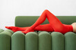 © Andriy Bezuglov/Stocksy - Model in bright red tights posing on green sofa